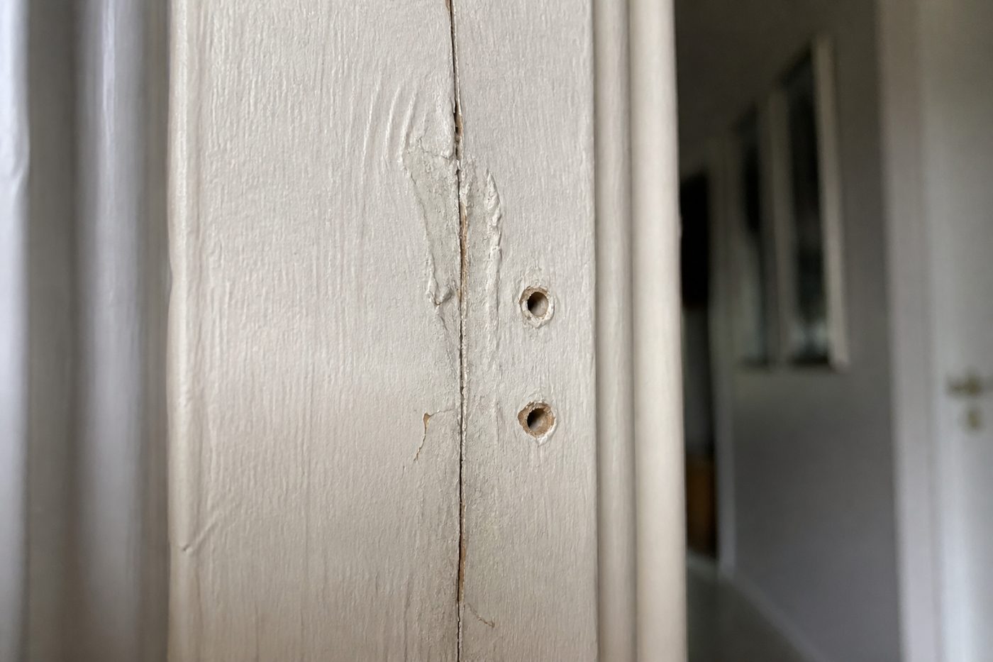 A split in a door frame, filled and painted over